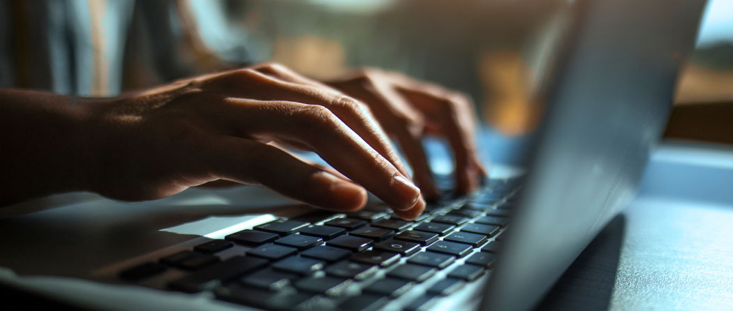 close-up of hands using a laptop keyboard