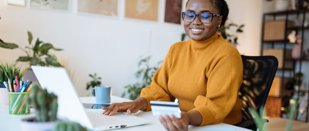 woman using a laptop and holding a credit card